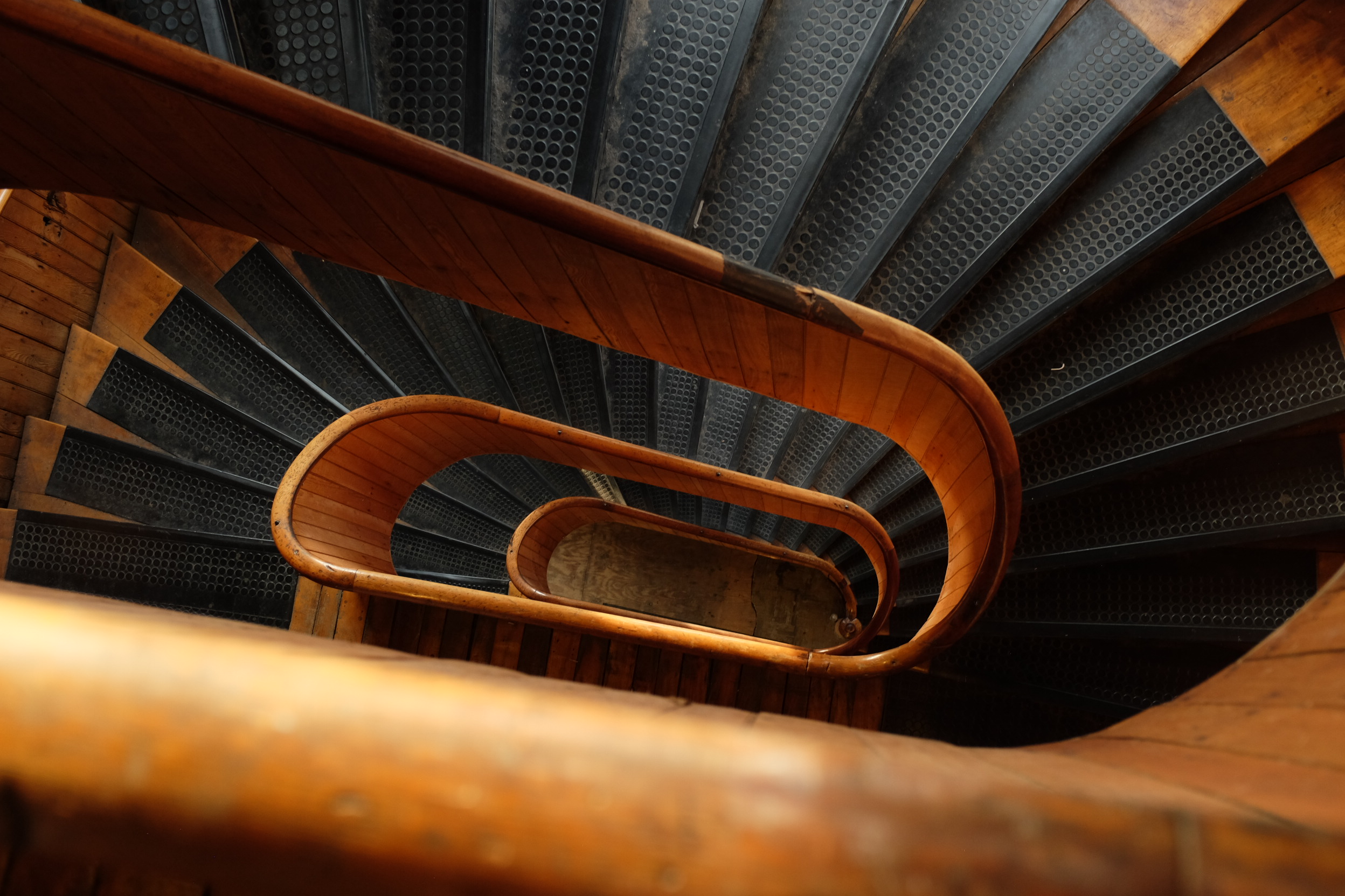 A photo looking down the center of a wooden spiral staircase.