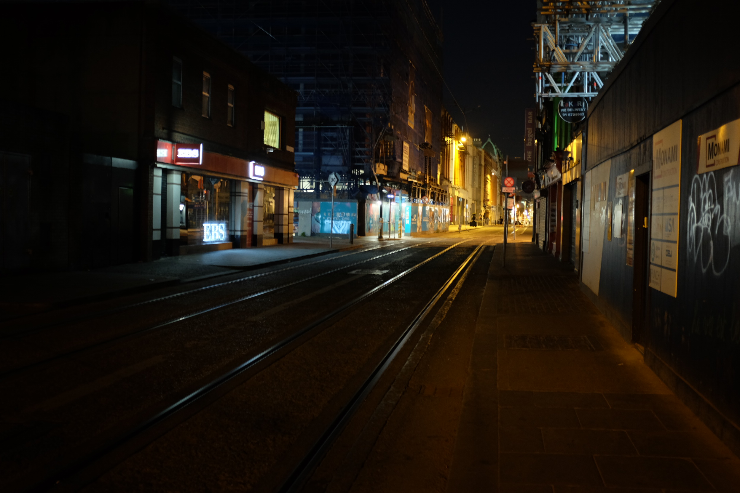 A photo of train rails in a city at night.
